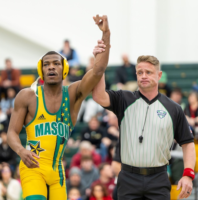 A referee raises the arm of a victorious Mason wrestler
